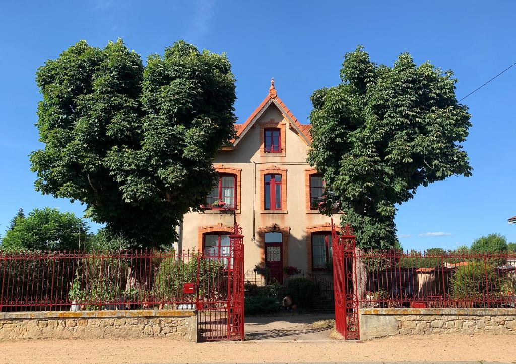 ein altes Haus mit einem roten Tor und zwei Bäumen in der Unterkunft MAS TERRE Chambres d'Hôtes in Lezoux