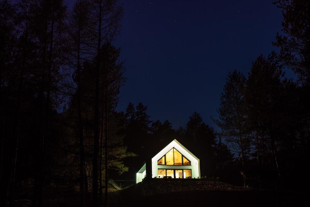 een klein huis verlicht in de nacht in het bos bij Źródło Energii in Małastów