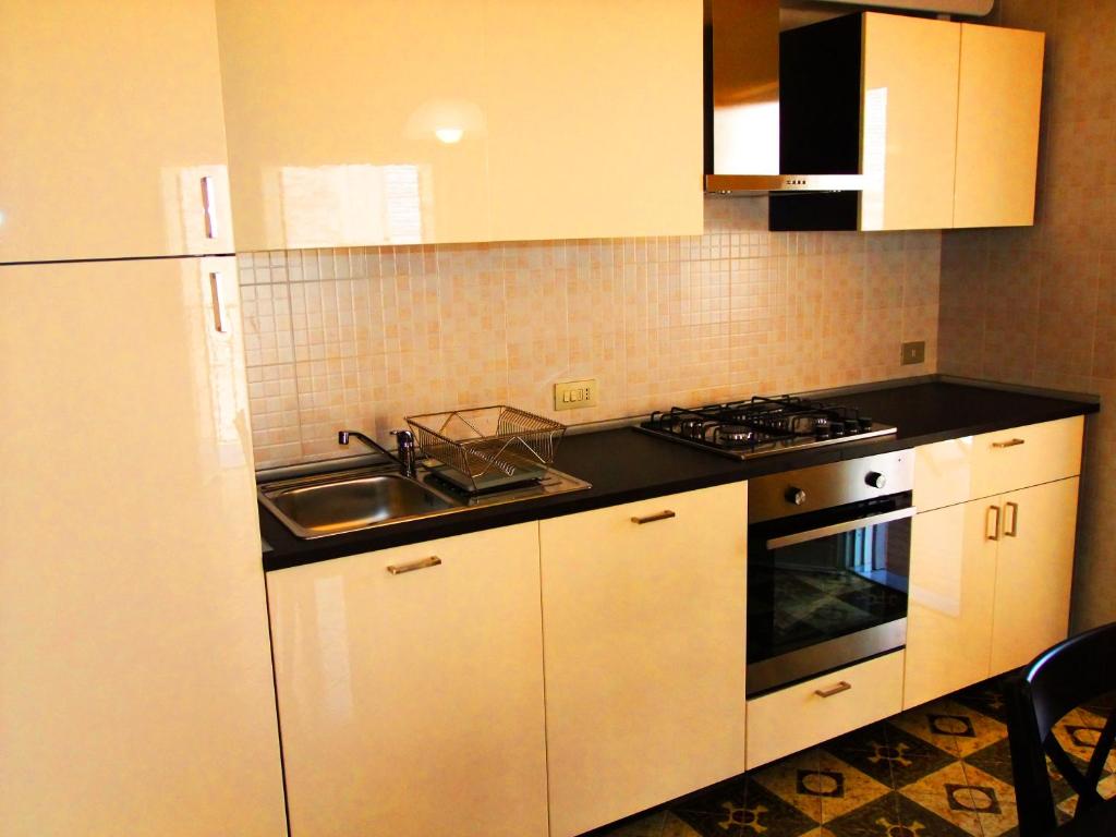 a kitchen with white cabinets and a sink and a stove at Casa Barranco in Cefalù