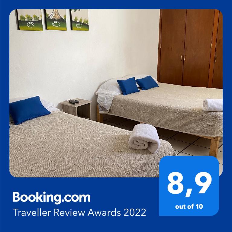 two beds in a hotel room with a sign that says travel review awards at Casa Ejecutivo Zona Iteso Bahía de Acapulco in Guadalajara