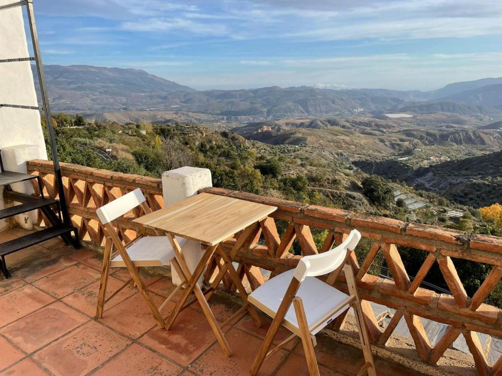 einen Holztisch und Stühle auf einem Balkon mit Aussicht in der Unterkunft Apartamentos El Cabo in Mairena