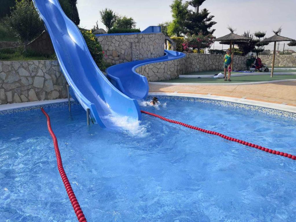 a blue water slide in a swimming pool at AH RENTALS Acualandia Apartamento in Peniscola