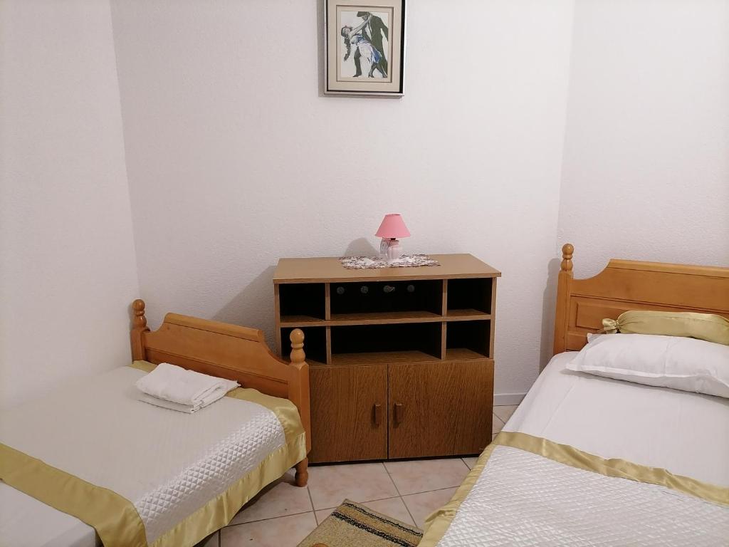 a bedroom with two beds and a dresser with a lamp on it at Apartment 3a, first floor in Rogoznica