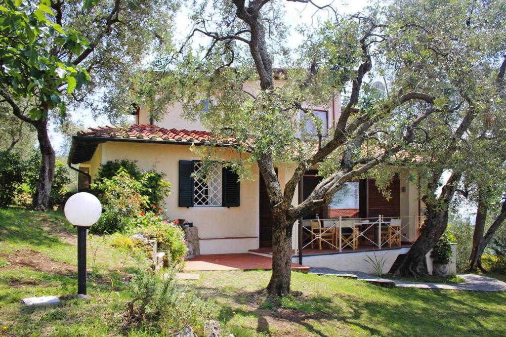 a small white house with a porch and trees at Holiday home, Monteggiori in Santa Lucia