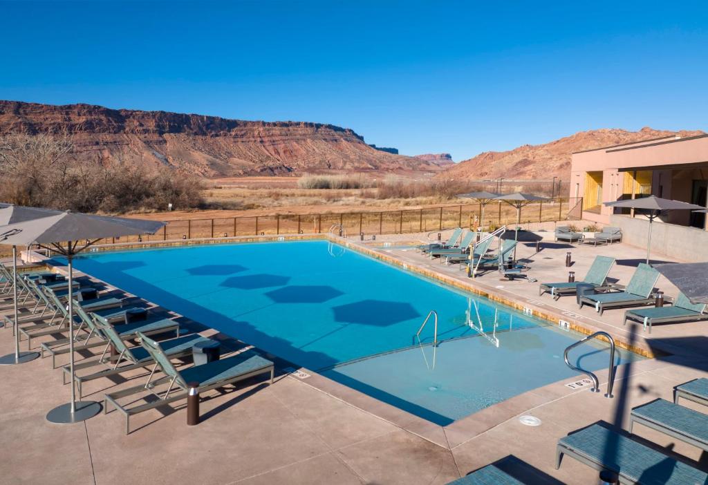 a swimming pool with chairs and mountains in the background at The Moab Resort, WorldMark Associate in Moab