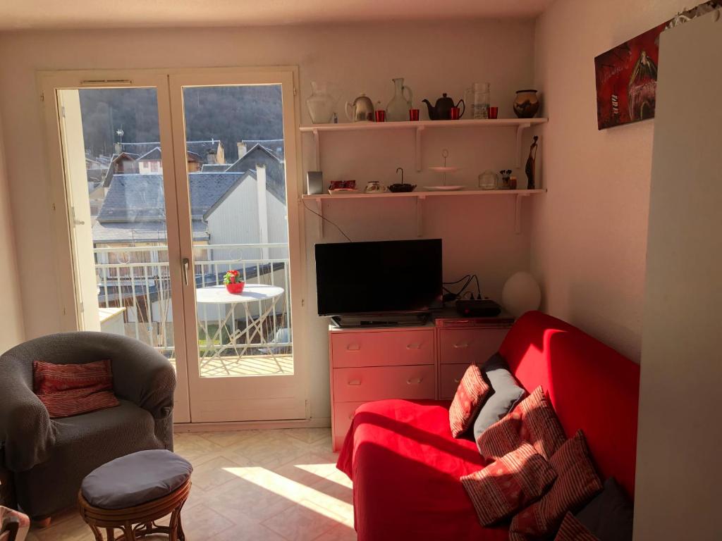 salon z czerwoną kanapą i telewizorem w obiekcie Les Jardins du Casino T2 bis- 4 personnes-Tarif cures w mieście Luchon