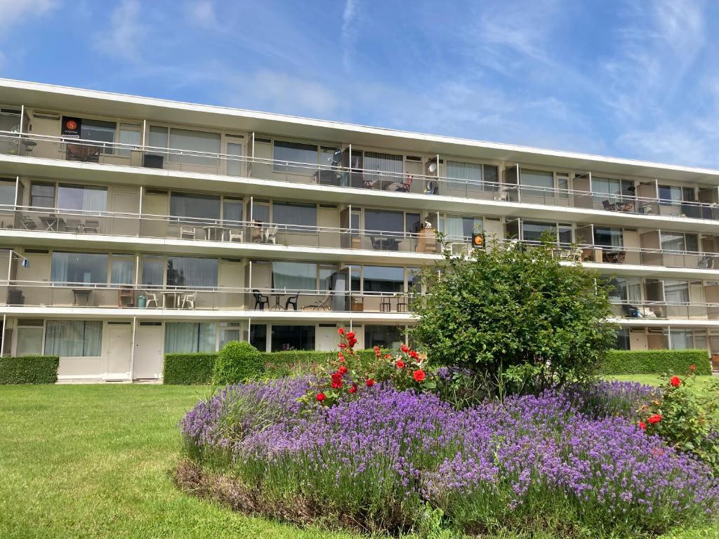 ein Apartmenthaus mit Blumen davor in der Unterkunft Lovely Acacia in De Haan