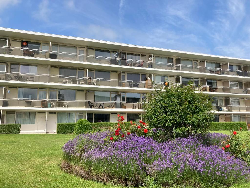 an apartment building with flowers in front of it at Lovely Acacia in De Haan