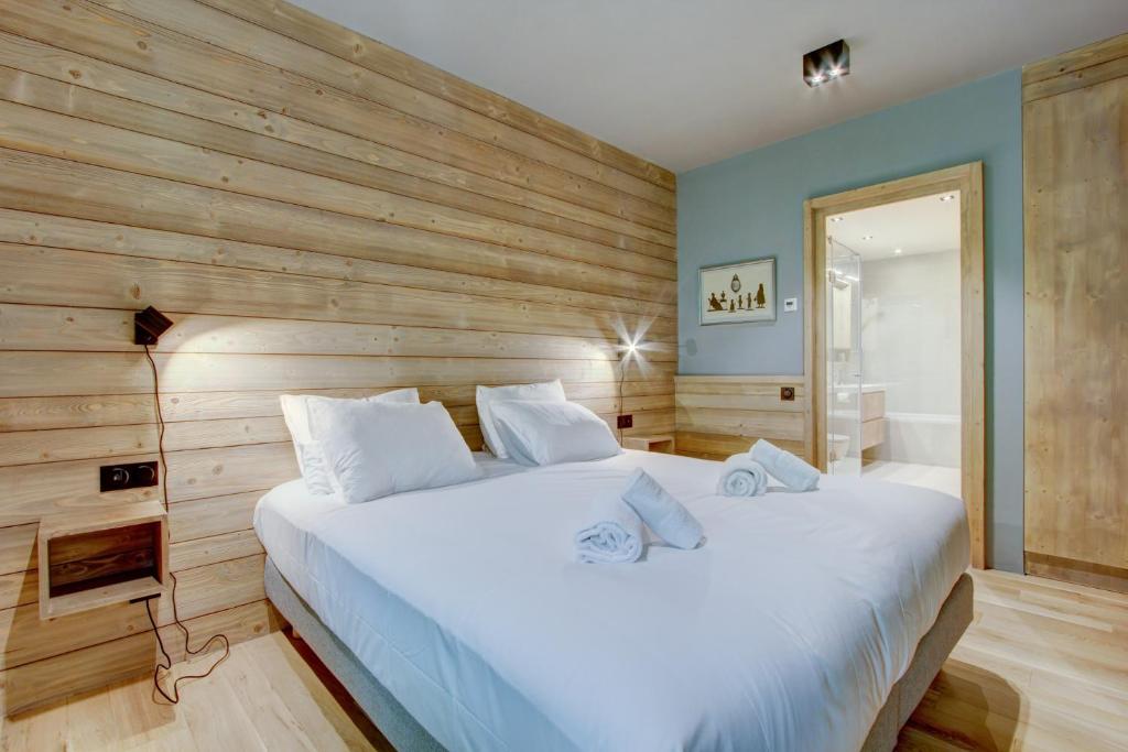 a bedroom with a large white bed with a wooden wall at Chalet La Mésange Boréale in Morzine