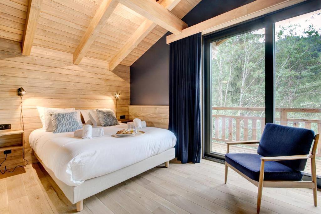 a bedroom with a bed and a chair and a window at Chalet La Mésange Boréale in Morzine