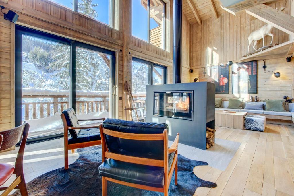 a living room with a fireplace and a table and chairs at Chalet La Mésange Boréale in Morzine