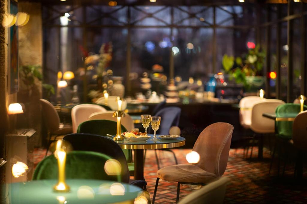 un restaurant avec des chaises, des tables et des verres à vin dans l'établissement Hôtel De Charme Le Chêne Vert, à Brive-la-Gaillarde