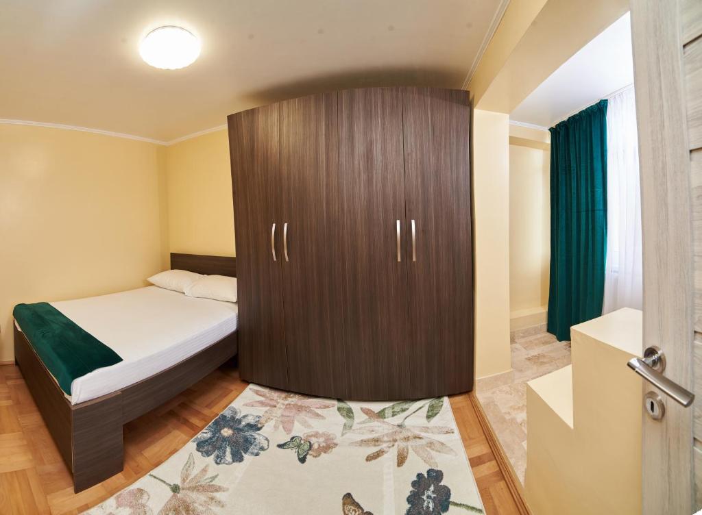 Schlafzimmer mit einem Bett und einem Holzschrank in der Unterkunft Star Apartment in Timişoara