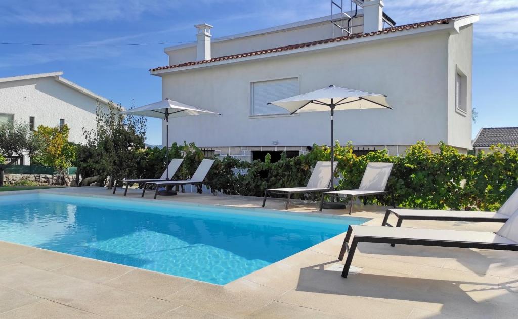 una piscina con sedie e ombrelloni davanti a una casa di Villa D'Uvale Douro ad Alijó