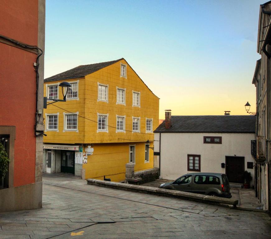 un edificio amarillo con un coche aparcado en una calle en Pension Escalinata en Sarria