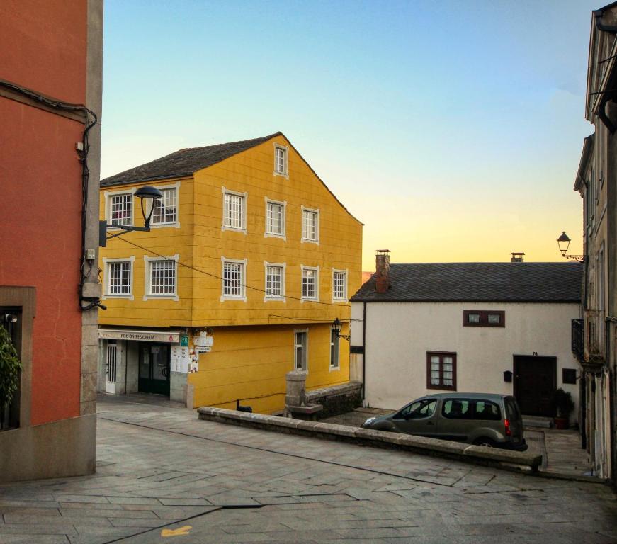 un edificio amarillo con un coche aparcado en una calle en Pension Escalinata, en Sarria