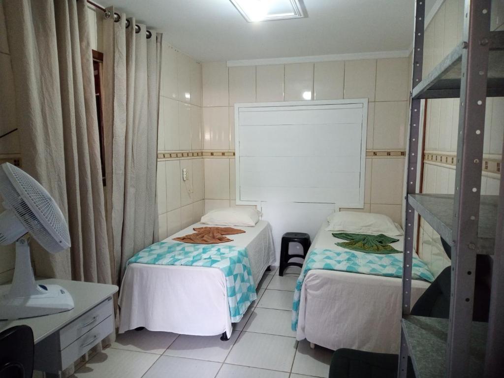 a small room with two beds and a shelf at Pousada Joinville in Joinville