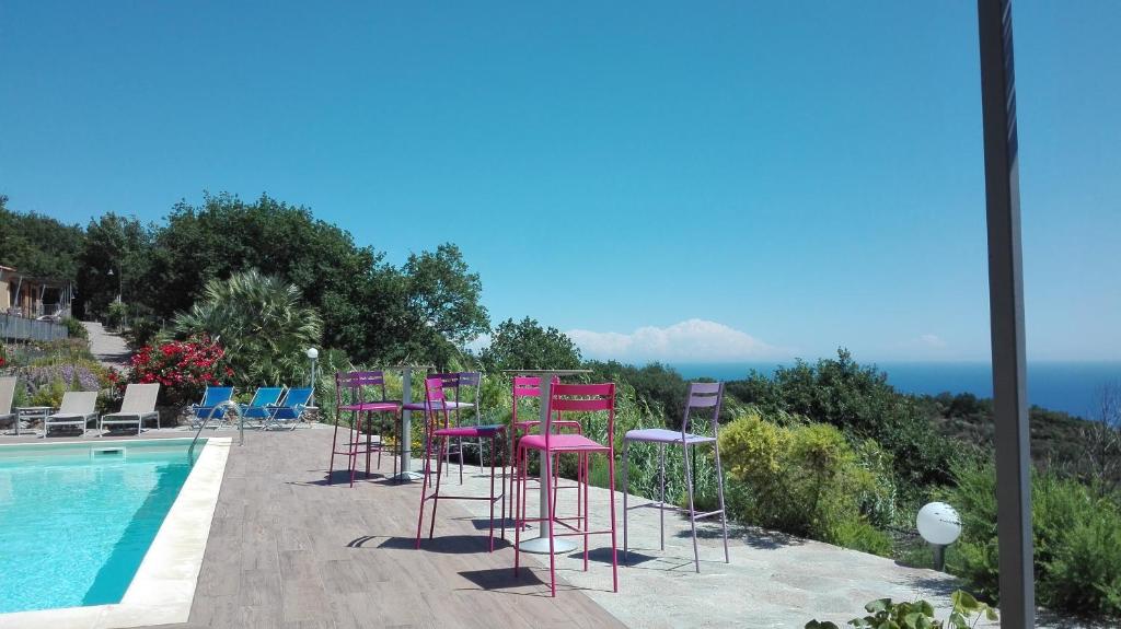 a row of pink chairs and tables next to a swimming pool at Oroverde in Bergeggi