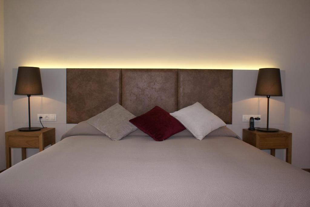 a bedroom with a large bed with two lamps at Aparthotel K in Figueres