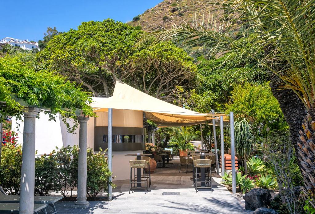 a patio with a table and chairs and trees at Hotel Parco Smeraldo Terme in Ischia