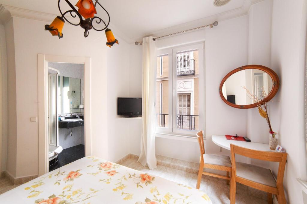 1 dormitorio con cama, espejo y escritorio en Hostal Barrera, en Madrid