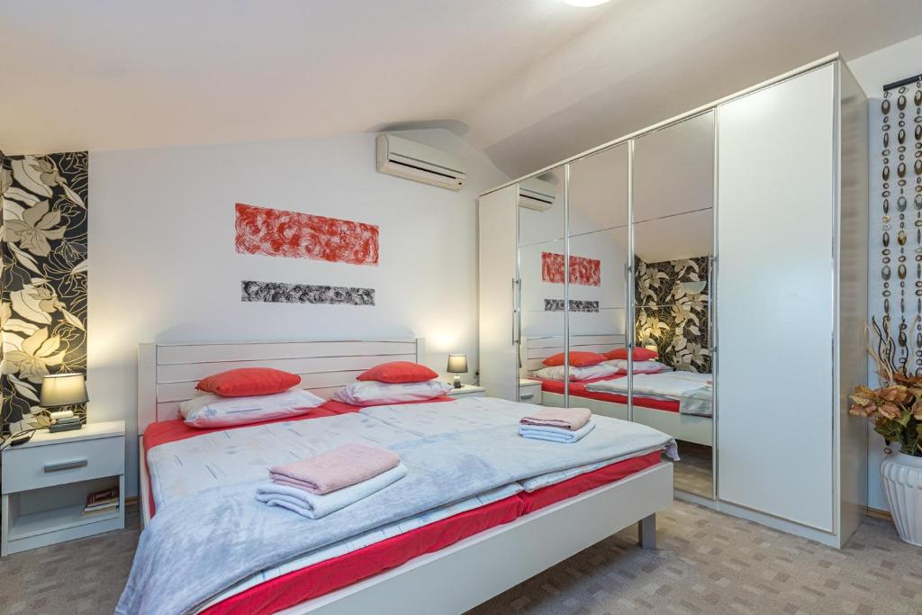 a bedroom with a bed with red pillows and a mirror at Apartment Teri in Nova Vas
