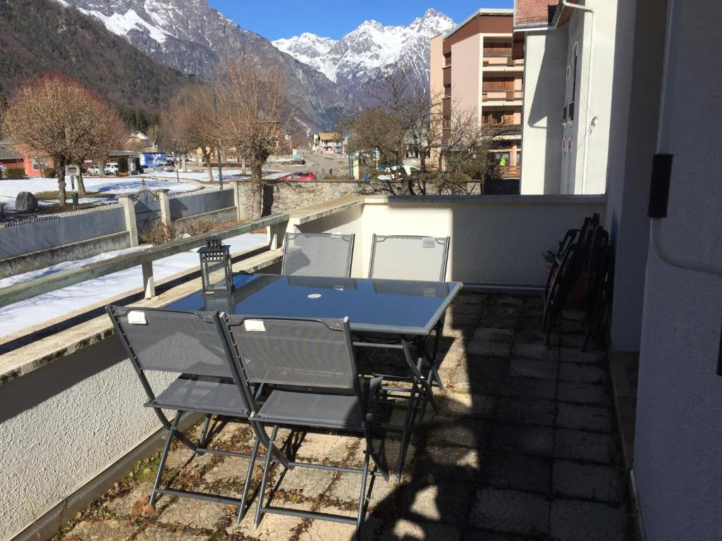 a table and chairs on a balcony with a view of mountains at Superbe appartement à Bourg d'Oisans avec terrasse Sud in Le Bourg-dʼOisans