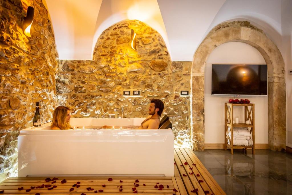 two women sitting in a bath tub in a room with a stone wall at La Rondine in Tagliacozzo