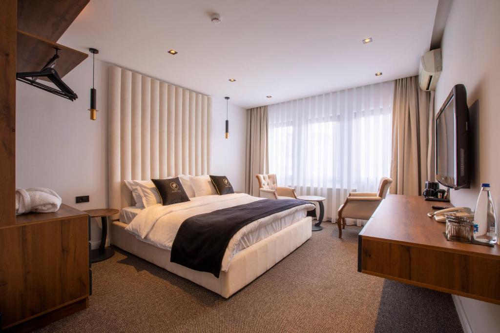 pokój hotelowy z łóżkiem i telewizorem w obiekcie Plaza Boutique Hotel w Prisztinie