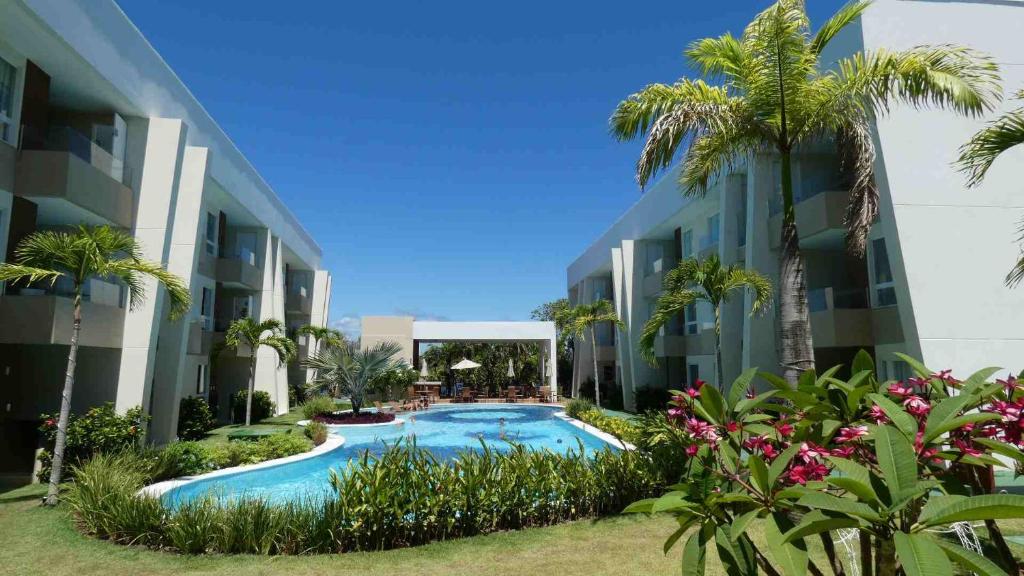 uma piscina no meio de um edifício com palmeiras em Praia de Guarajuba-Porto Smeralda em Guarajuba
