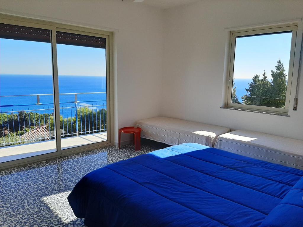 a bedroom with a blue bed and a large window at Hotel Conca d'Oro in Stalettì