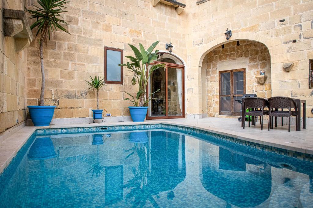 a swimming pool in a house with a stone wall at Ta Gorga Holiday Farmhouse with Private Pool in Xewkija