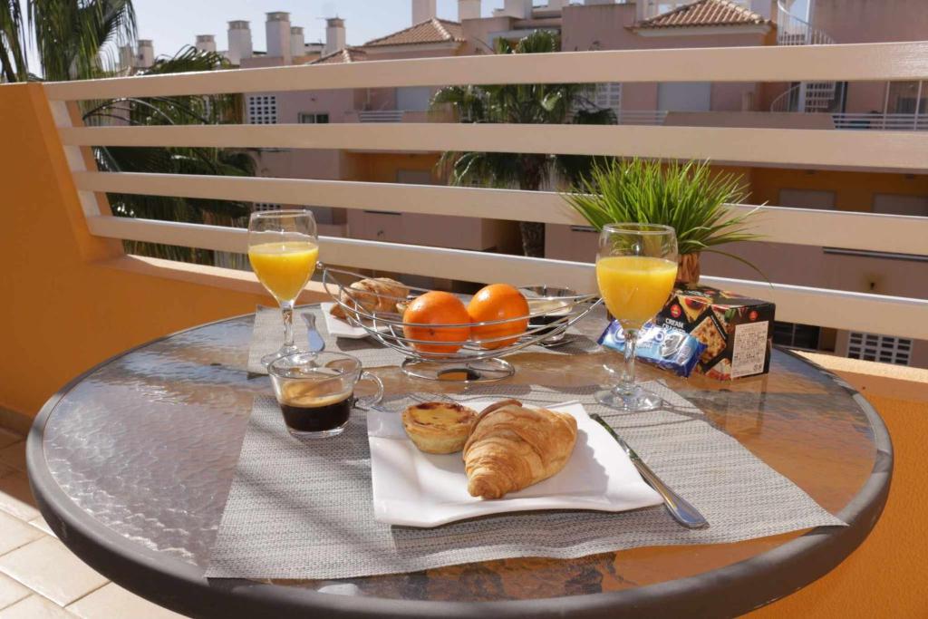 einen Tisch mit einem Tablett mit Speisen und Gläsern Orangensaft in der Unterkunft Apartamento Maresia T2 Penthouse by Your Home Algarve in Cabanas de Tavira