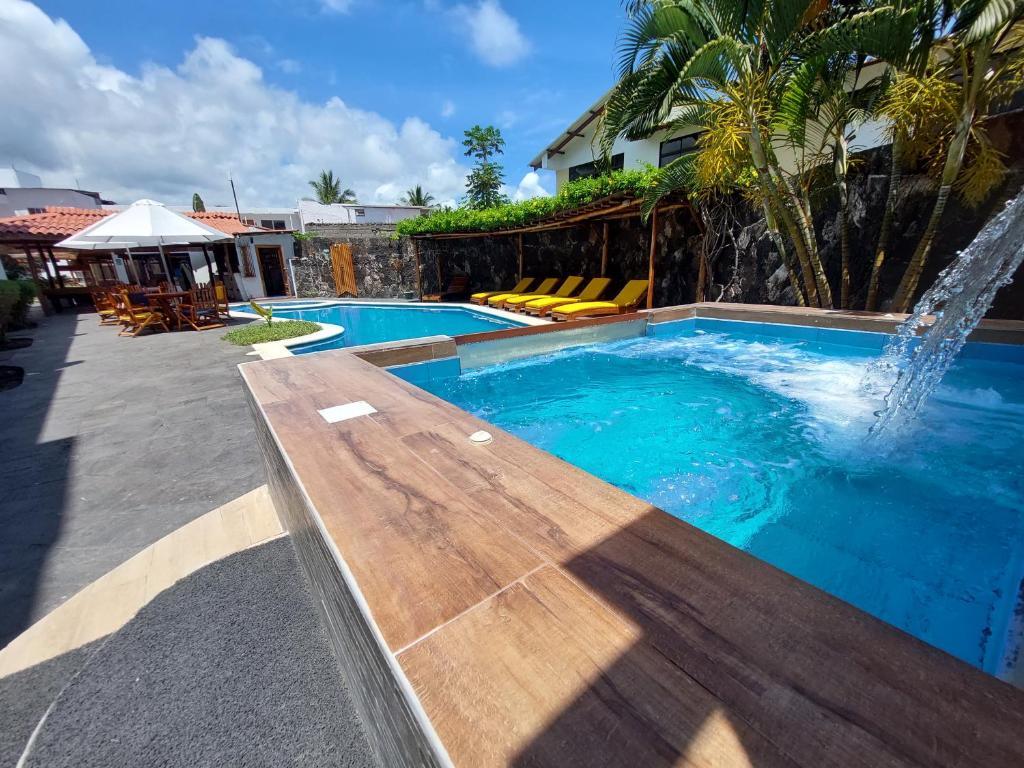una piscina con un banco de madera y una fuente de agua en Hotel Las Ninfas, en Puerto Ayora
