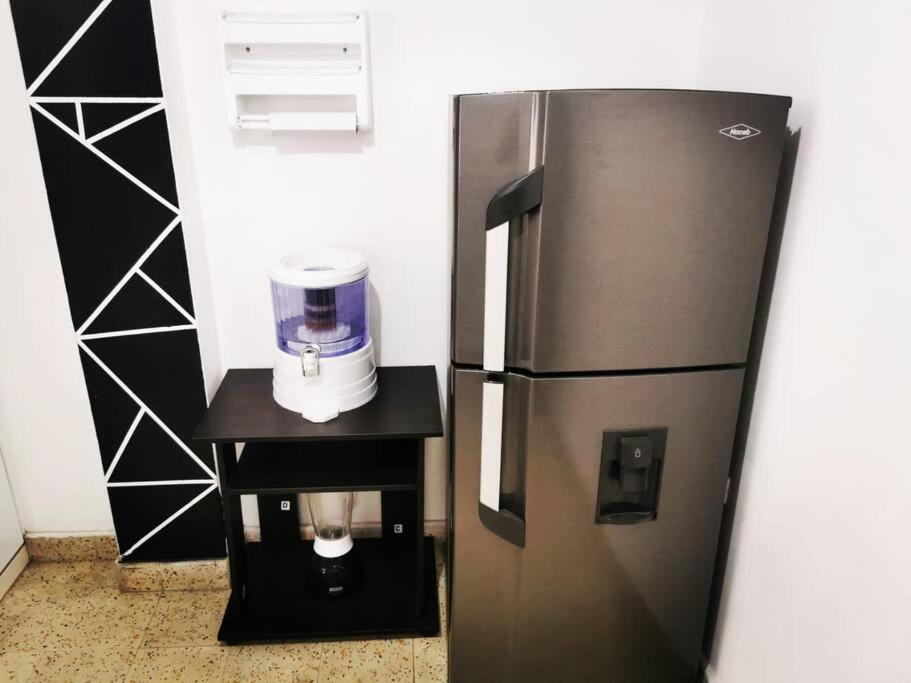 a stainless steel refrigerator with a coffee maker on a stand at Hermoso apartamento en el centro histórico de San Gil I 2 in San Gil