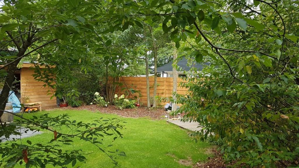 een achtertuin met een hek en een tuin met groen gras bij Vakantiewoning Dinkelhofje met gratis linnen in Denekamp