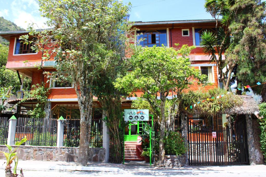 a house with a fence and trees in front of it at Hotel y Spa Isla de Baños in Baños