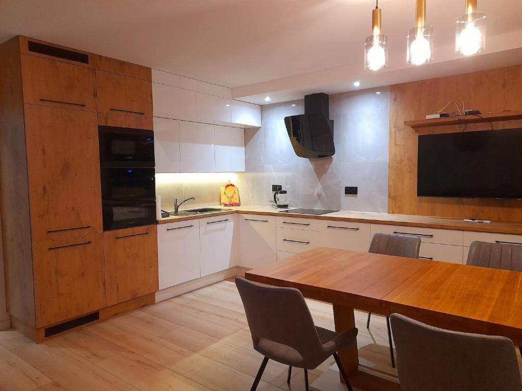 a kitchen with a wooden table and a tv on the wall at Apartament Nad wierzbami in Piechowice