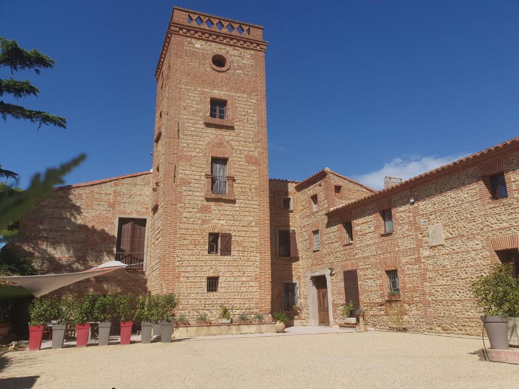 un gran edificio de ladrillo con una torre de reloj en Mas Miraflors en Perpiñán