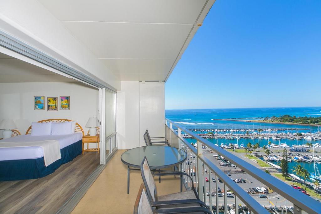 a bedroom with a bed and a balcony with a view of the ocean at Ilikai Tower 2141 Yacht Harbor View 1BR in Honolulu