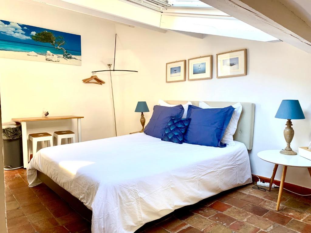 1 dormitorio con 1 cama blanca grande con almohadas azules en Le 1835, Studio Bleu-Coton, en Moustiers-Sainte-Marie
