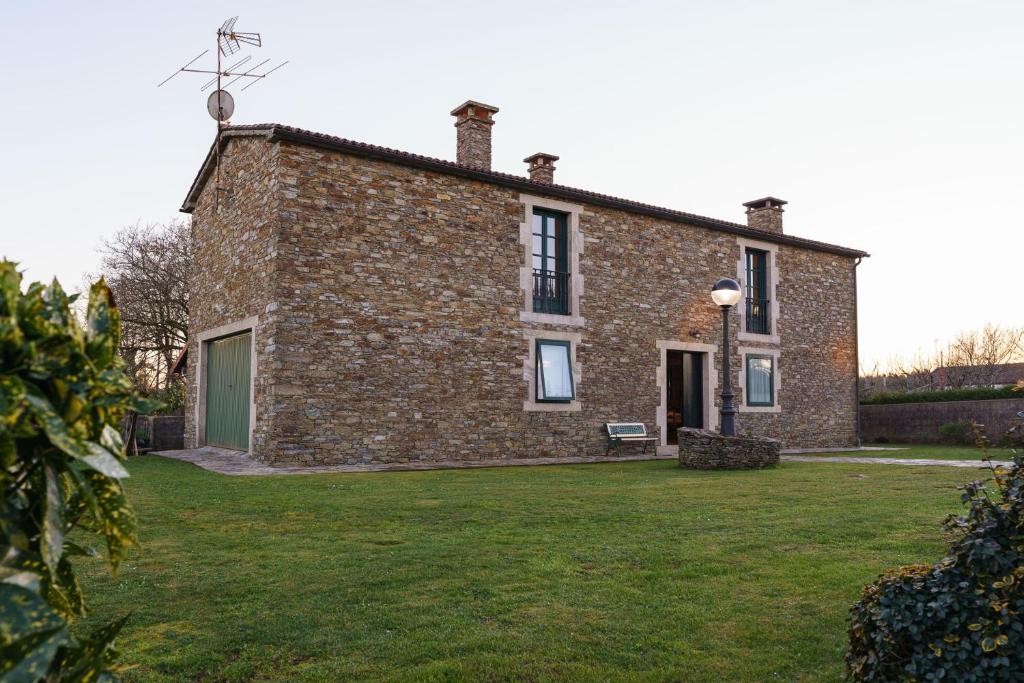 an old brick house with a grass yard at Casa Elvira in Marquiño