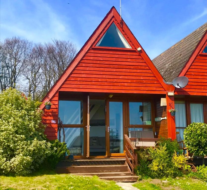 a cottage with a red roof and large windows at Clifftop Chalet With Pool in Deal