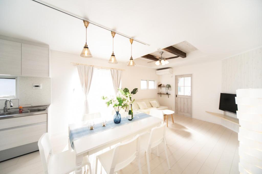 eine weiße Küche und ein Wohnzimmer mit einem Tisch und Stühlen in der Unterkunft Shizukinosato TSUKI Terrace 531 in Awaji