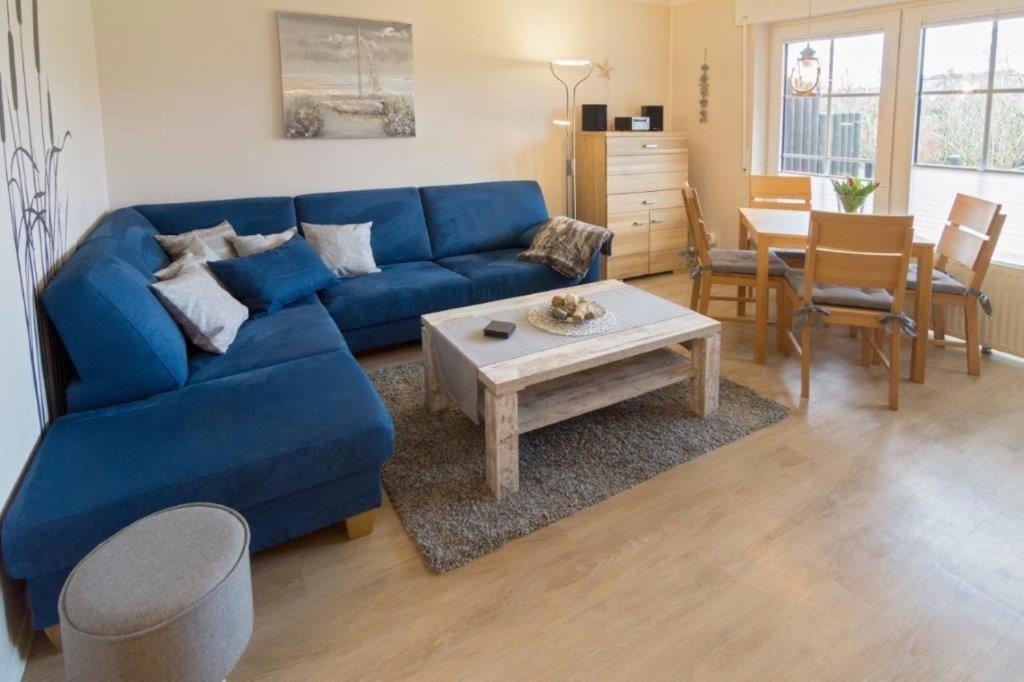 ein Wohnzimmer mit einem blauen Sofa und einem Tisch in der Unterkunft Fewo Jolle D11 - Haustiere erlaubt - WLAN kostenlos in Norddeich