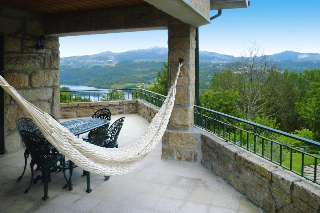 a patio with a hammock and chairs on a balcony at Granite House by Tâmega with Pool in Luzim