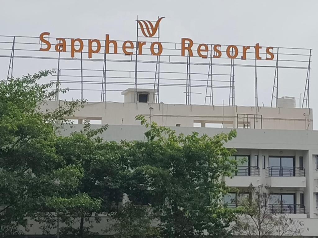 a sign on the side of a building with trees at Sapphero Resorts in Shirdi