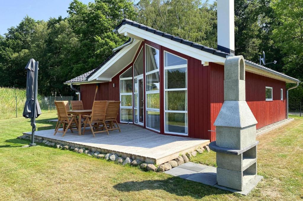 a red cabin with a deck and a table and chairs at Ferienhaus Larsson mit Sauna am Dümmer See, Dümmer in Dümmer