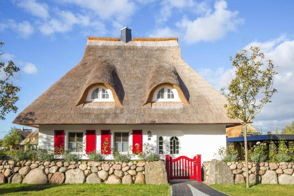 uma casa de palha com portas vermelhas e uma parede de pedra em Holiday house, Fuhlendorf em Fuhlendorf