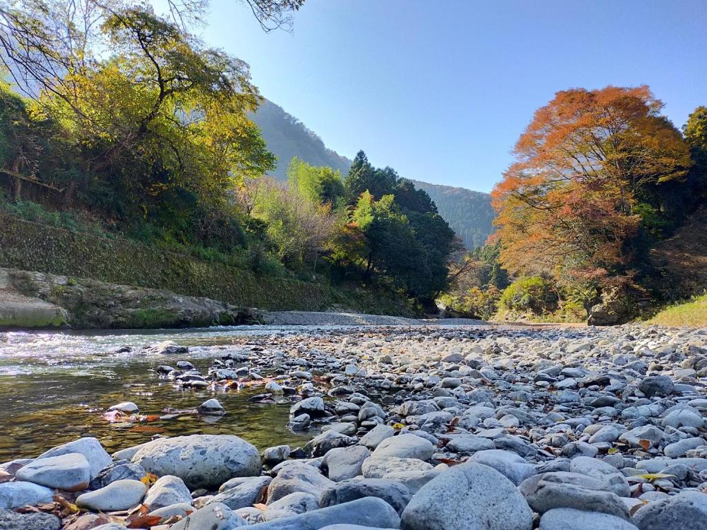 a river with rocks and trees in the background at Otsu Nature Garden in Akiruno